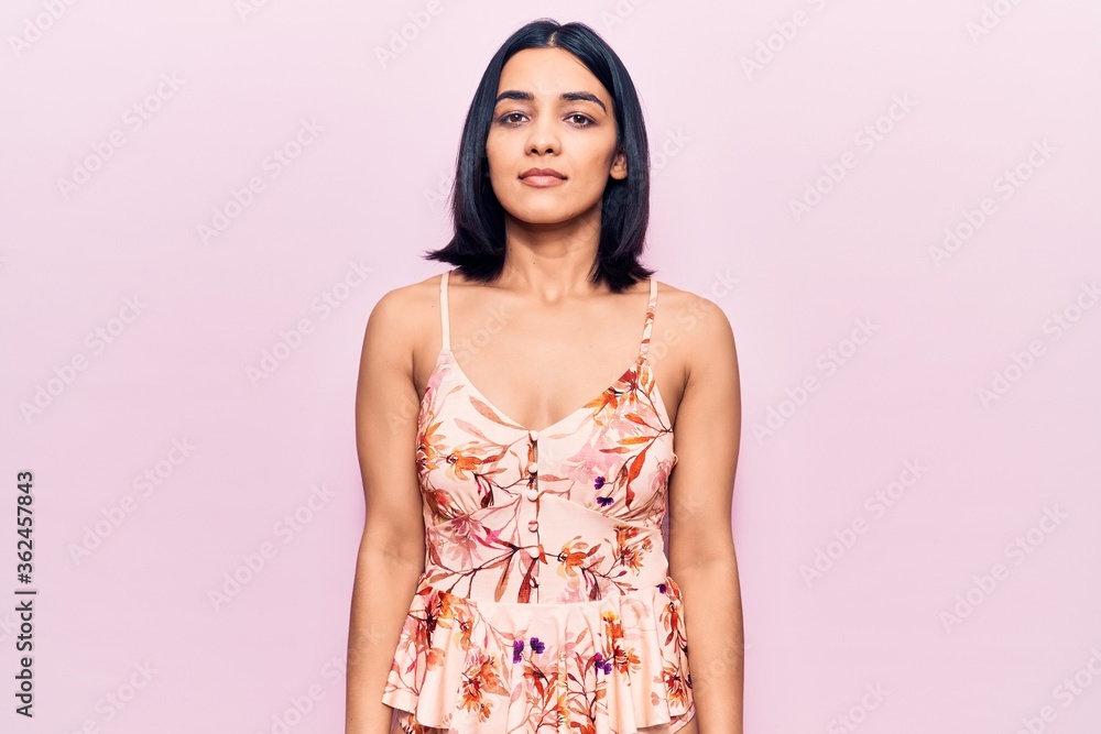 Young beautiful latin woman wearing casual clothes relaxed with serious expression on face. simple and natural looking at the camera. Young beautiful latin woman wearing casual clothes relaxed with serious expression on face. simple and natural looking at the camera.