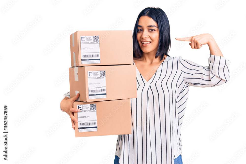 Young beautiful latin woman holding delivery package pointing finger to one self smiling happy and proud Young beautiful latin woman holding delivery package pointing finger to one self smiling happy and proud