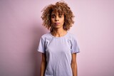 Young beautiful african american woman wearing casual t-shirt standing over pink background with serious expression on face. Simple and natural looking at the camera.
