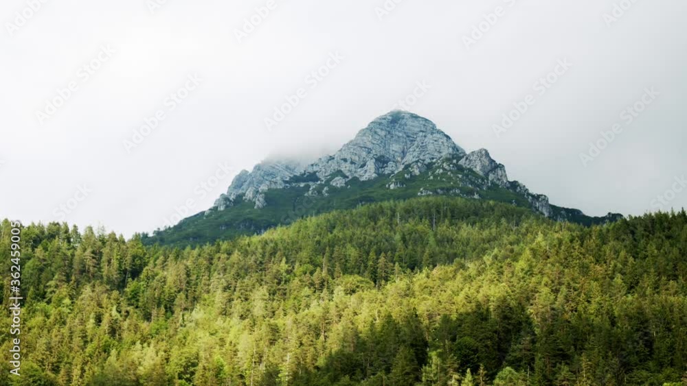 Time-lapse of clouds moving over mountain St. Ulrich in Pillersee Tyrol, Austria. Surrounded by dense and green coniferous forest. Time-lapse of clouds moving over mountain St. Ulrich in Pillersee Tyrol, Austria. Surrounded by dense and green coniferous forest.