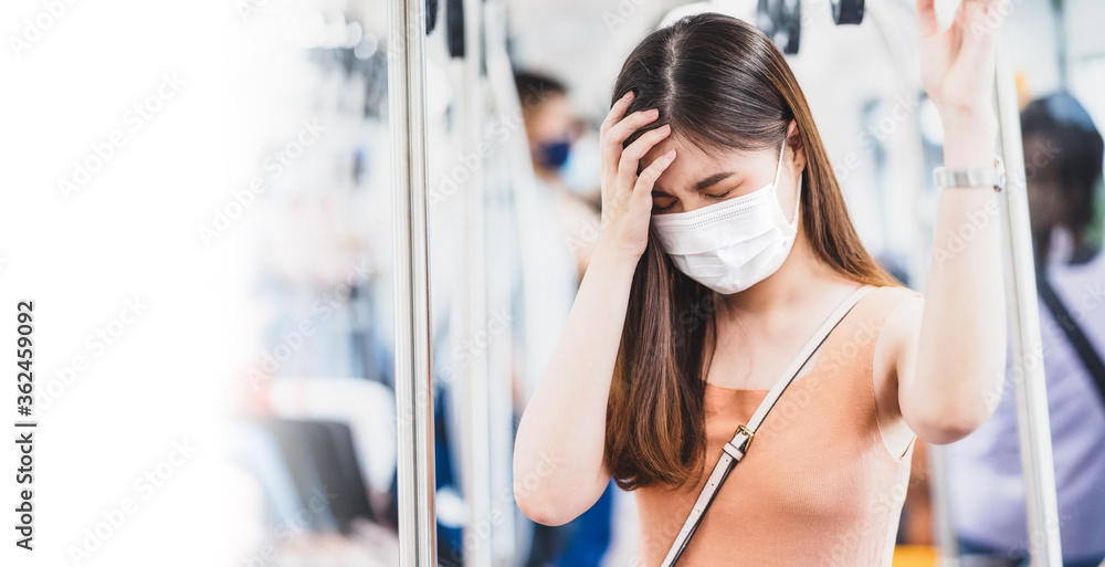 Young Asian woman passenger wearing surgical mask and Having a headache in subway train when traveling in big city at Covid19 outbreak, Infection and Pandemic,new normal and illness prevention concept