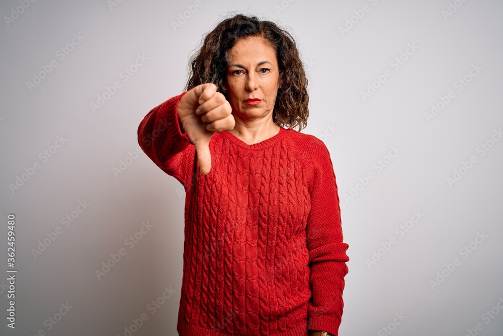 Middle age brunette woman wearing casual sweater standing over isolated white background looking unhappy and angry showing rejection and negative with thumbs down gesture. Bad expression. Middle age brunette woman wearing casual sweater standing over isolated white background looking unhappy and angry showing rejection and negative with thumbs down gesture. Bad expression.