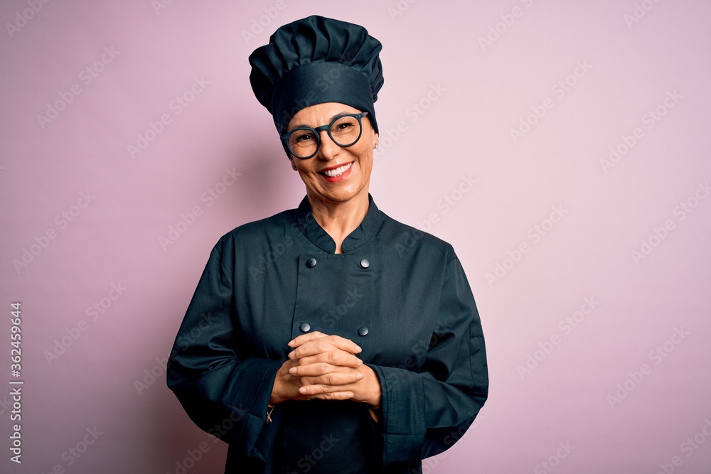Middle age brunette chef woman wearing cooker uniform and hat over isolated pink background with hands together and crossed fingers smiling relaxed and cheerful. Success and optimistic Middle age brunette chef woman wearing cooker uniform and hat over isolated pink background with hands together and crossed fingers smiling relaxed and cheerful. Success and optimistic