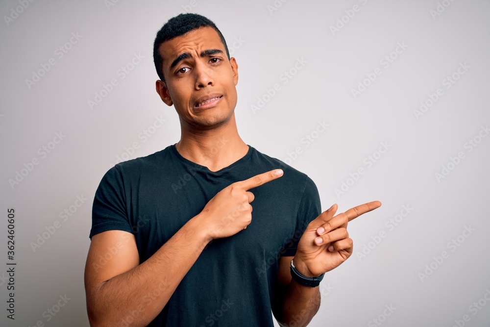 Young handsome african american man wearing casual t-shirt standing over white background Pointing aside worried and nervous with both hands, concerned and surprised expression Young handsome african american man wearing casual t-shirt standing over white background Pointing aside worried and nervous with both hands, concerned and surprised expression