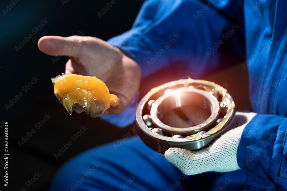 Mechanic is putting yellow grease in the into bearing, engineering and industrial concept. Mechanic is putting yellow grease in the into bearing, engineering and industrial concept.