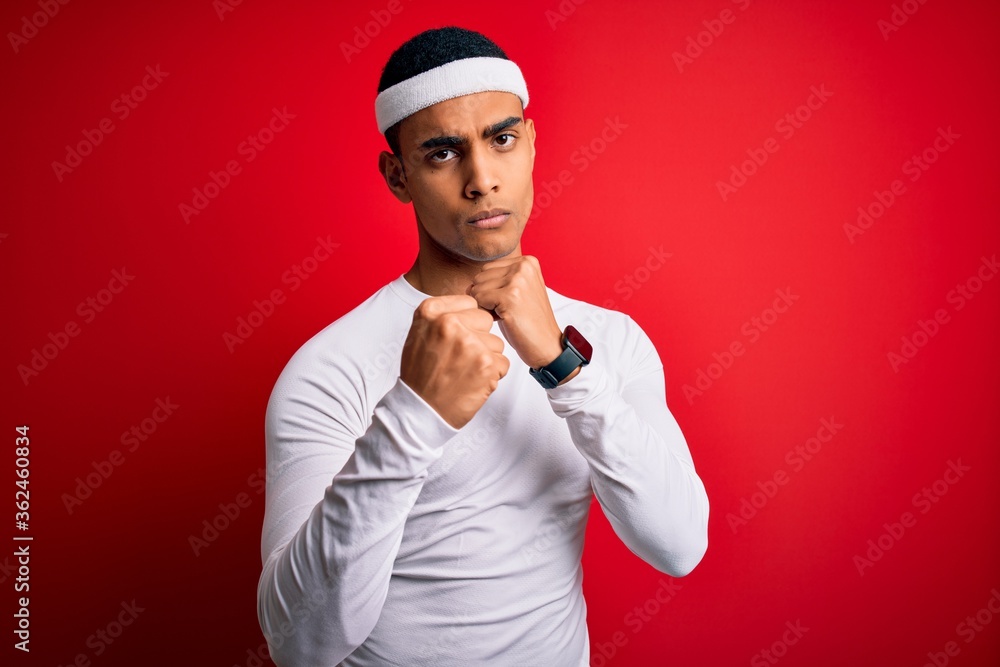 Young handsome african american sportsman wearing sportswear over red background Ready to fight with fist defense gesture, angry and upset face, afraid of problem
