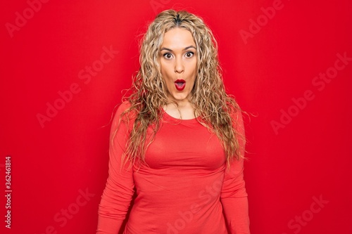 Young beautiful blonde woman wearing red casual t-shirt standing over isolated background afraid and shocked with surprise expression, fear and excited face. © Krakenimages.com