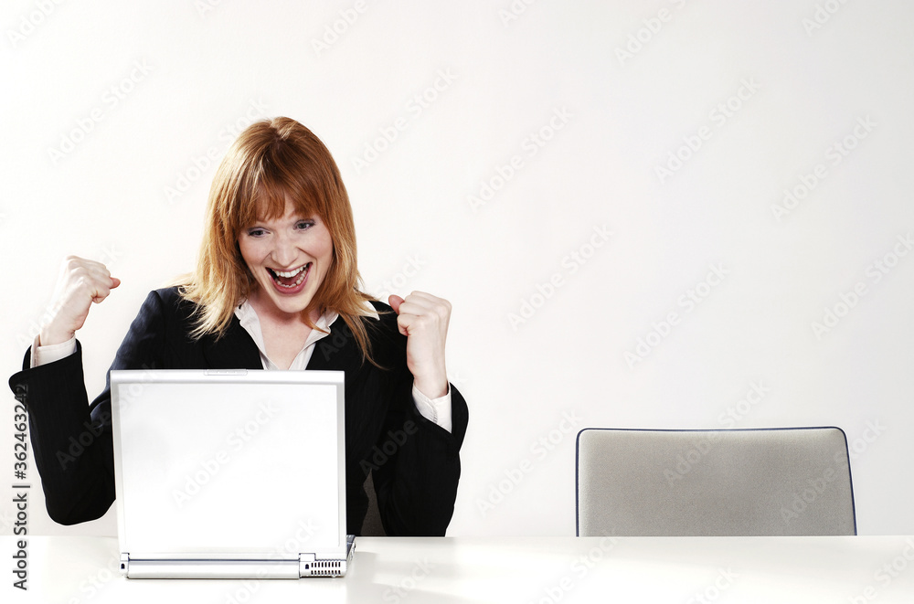 An overjoyed businesswoman after reading the good news on her laptop An overjoyed businesswoman after reading the good news on her laptop