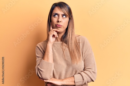Young beautiful woman wearing casual sweater thinking concentrated about doubt with finger on chin and looking up wondering