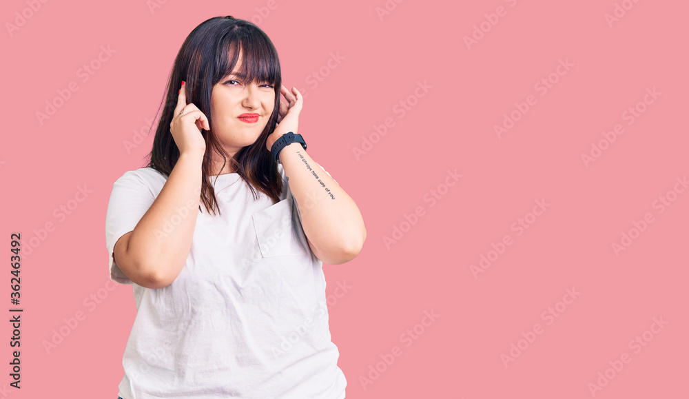 Young plus size woman wearing casual clothes covering ears with fingers with annoyed expression for the noise of loud music. deaf concept. Young plus size woman wearing casual clothes covering ears with fingers with annoyed expression for the noise of loud music. deaf concept.