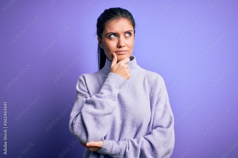 Young beautiful woman with blue eyes wearing casual turtleneck sweater over pink background with hand on chin thinking about question, pensive expression. Smiling with thoughtful face. Doubt concept. Young beautiful woman with blue eyes wearing casual turtleneck sweater over pink background with hand on chin thinking about question, pensive expression. Smiling with thoughtful face. Doubt concept.