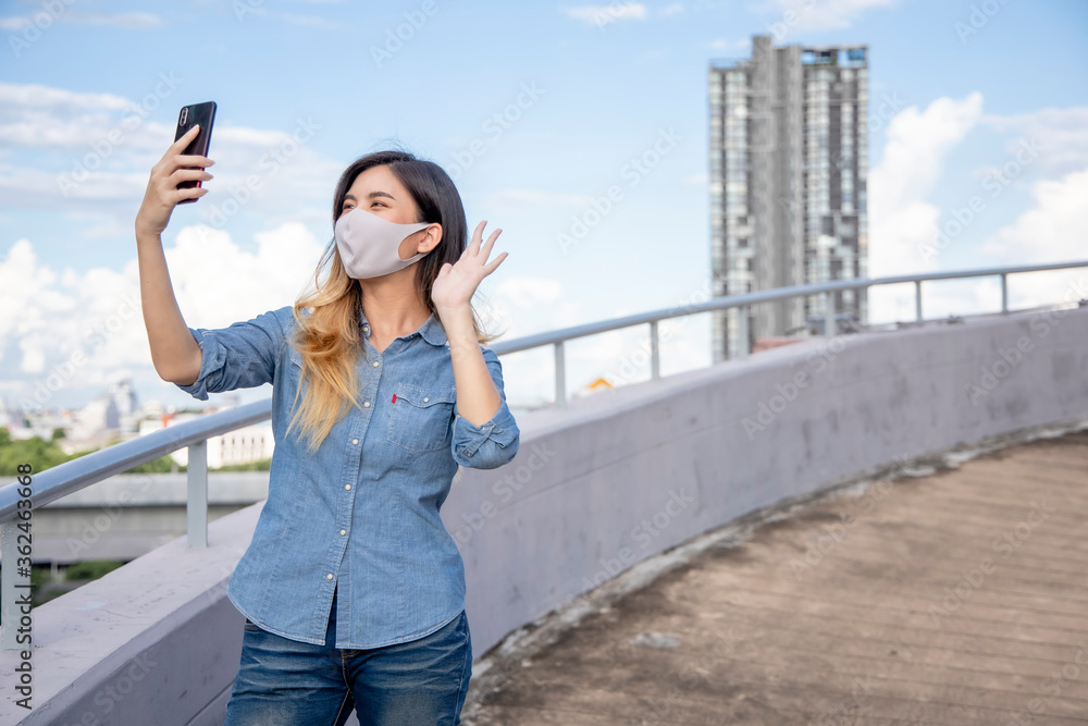 A woman wearing a mask is using a mobile phone to communicate over the internet.