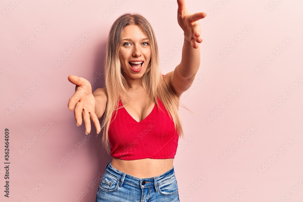 Young blonde woman wearing casual clothes looking at the camera smiling with open arms for hug. cheerful expression embracing happiness. Young blonde woman wearing casual clothes looking at the camera smiling with open arms for hug. cheerful expression embracing happiness.