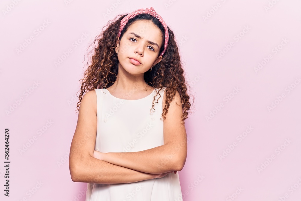 Beautiful kid girl with curly hair wearing casual clothes skeptic and nervous, disapproving expression on face with crossed arms. negative person. Beautiful kid girl with curly hair wearing casual clothes skeptic and nervous, disapproving expression on face with crossed arms. negative person.