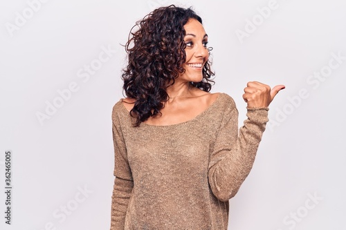 Middle age beautiful woman wearing casual sweater pointing thumb up to the side smiling happy with open mouth