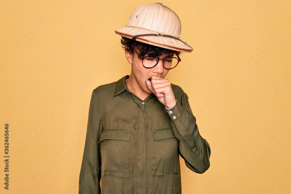 Young beautiful african american tourist woman wearing glasses and explorer hat feeling unwell and coughing as symptom for cold or bronchitis. Health care concept. Young beautiful african american tourist woman wearing glasses and explorer hat feeling unwell and coughing as symptom for cold or bronchitis. Health care concept.