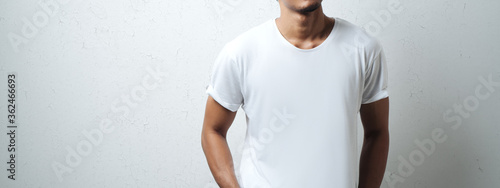 man in white blank t-shirt, grunge wall, studio portrait. Wide screen, panoramic