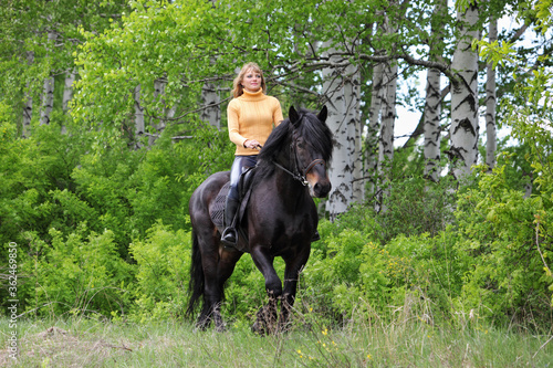 Beautiful blond girl with black horse in summer forest. Mare, animal © horsemen