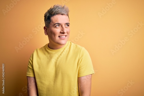 Young handsome modern man wearing yellow shirt over yellow isolated background smiling looking to the side and staring away thinking. © Krakenimages.com