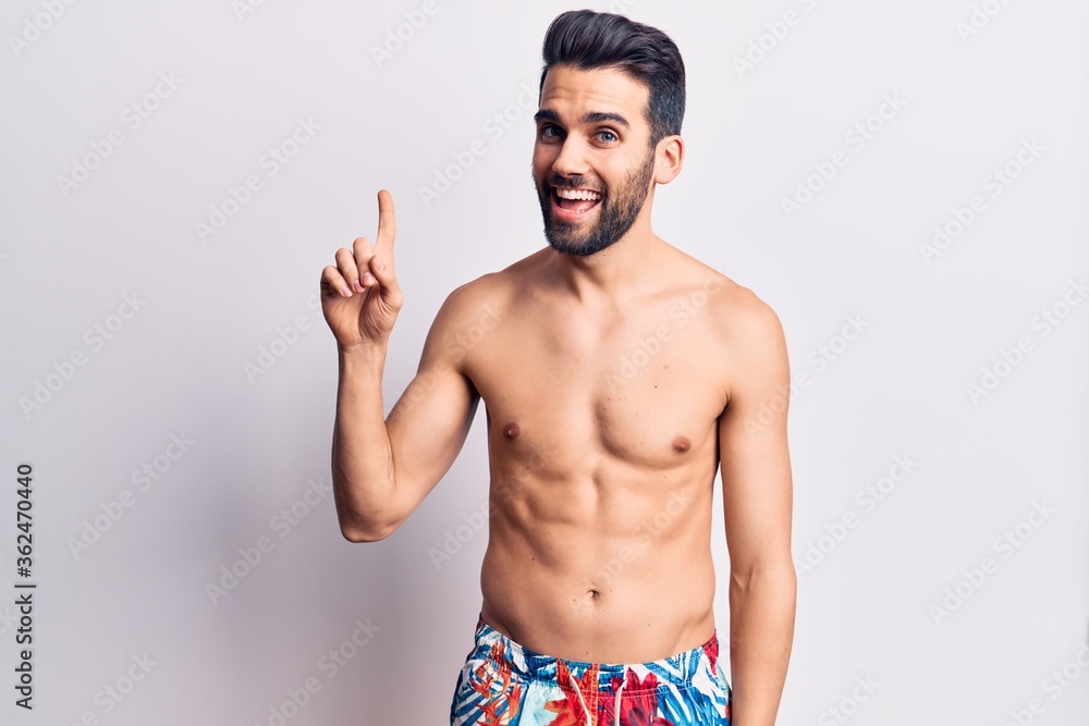 Young handsome man with beard shirtless wearing swimwear smiling with an idea or question pointing finger up with happy face, number one