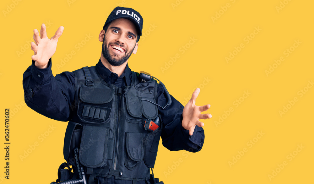 Young handsome man with beard wearing police uniform looking at the camera smiling with open arms for hug. cheerful expression embracing happiness. Young handsome man with beard wearing police uniform looking at the camera smiling with open arms for hug. cheerful expression embracing happiness.