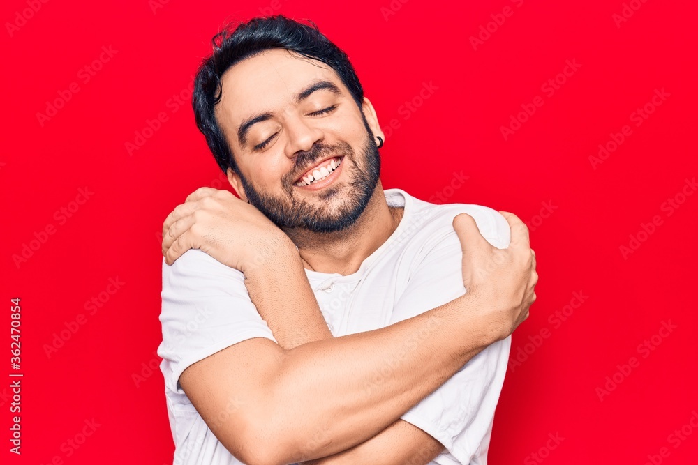 Young hispanic man wearing casual clothes hugging oneself happy and positive, smiling confident. self love and self care Young hispanic man wearing casual clothes hugging oneself happy and positive, smiling confident. self love and self care