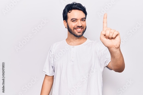 Young hispanic man wearing casual clothes showing and pointing up with finger number one while smiling confident and happy. © Krakenimages.com