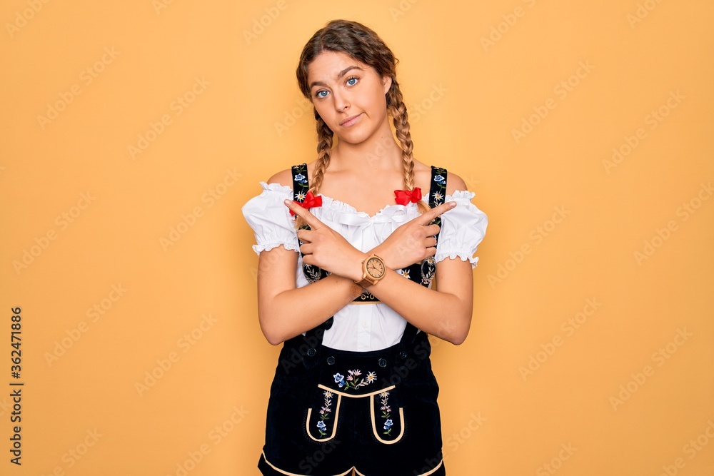 Young beautiful blonde german woman with blue eyes wearing traditional octoberfest dress Pointing to both sides with fingers, different direction disagree Young beautiful blonde german woman with blue eyes wearing traditional octoberfest dress Pointing to both sides with fingers, different direction disagree
