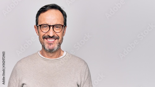 Middle age handsome man wearing casual sweater and glasses over isolated white background with a happy and cool smile on face. Lucky person. photo
