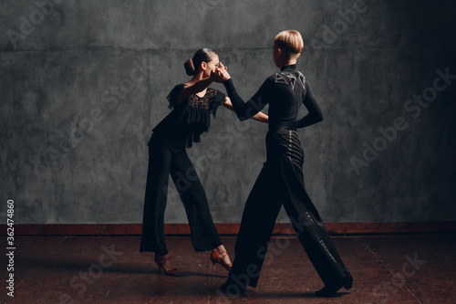 Couple in black costumes dancing in ballroom rumba dance