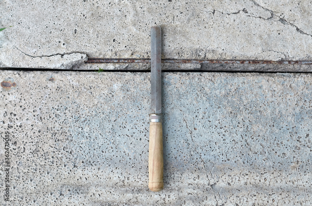 metal hand file with old wooden handle on concrete background metal hand file with old wooden handle on concrete background