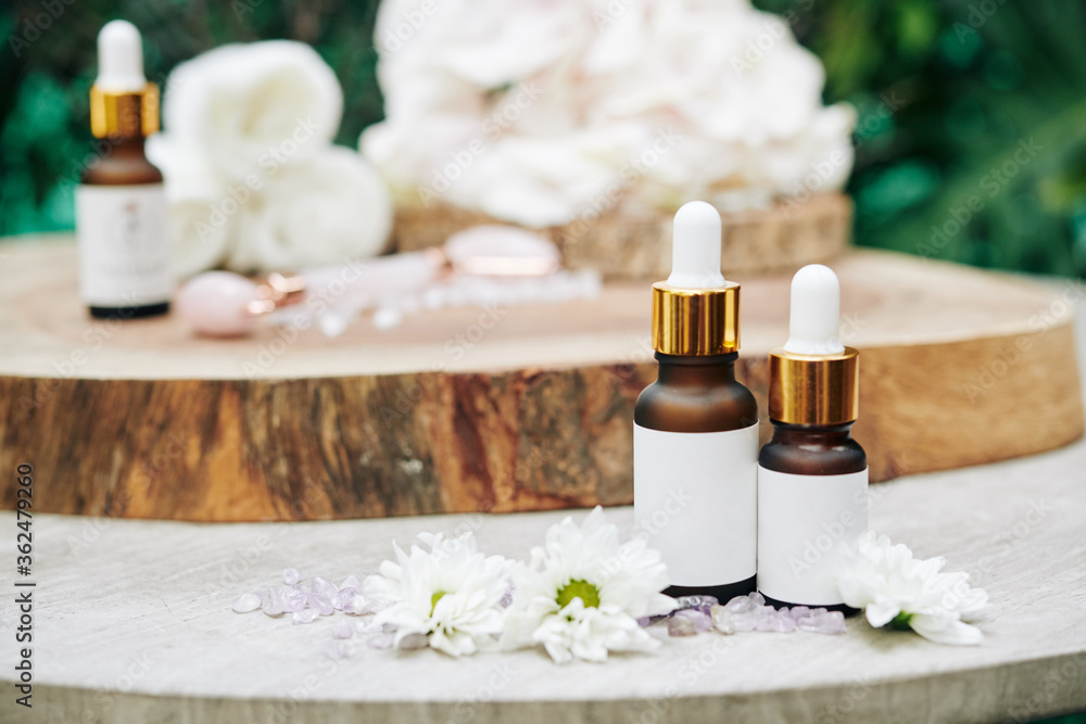 Beauty products like oils and serums on table with small flowers around Beauty products like oils and serums on table with small flowers around
