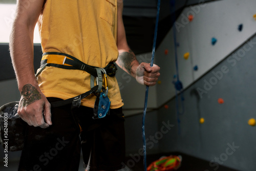 Chalked, locked and ready to rock. Cropped shot of sportive man holding rope, hands in white dust of magnesia, chalk, ready for climbing wall in bouldering center