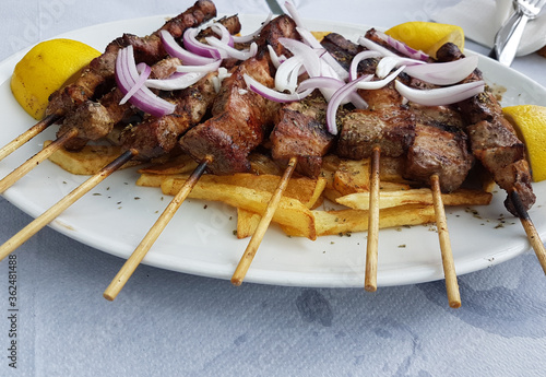 souvlakia greek tranditional food of meat onion lemon and potatoes in a plate photo