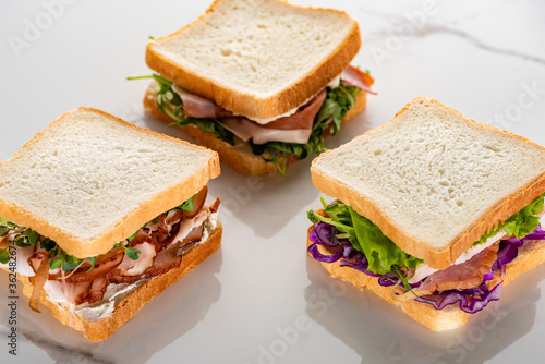 fresh green sandwiches with meat on marble white surface