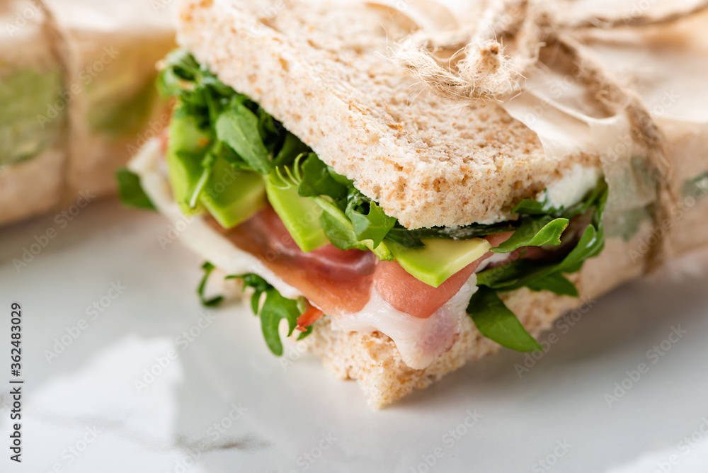 close up view of fresh green sandwich with jamon on marble white surface close up view of fresh green sandwich with jamon on marble white surface