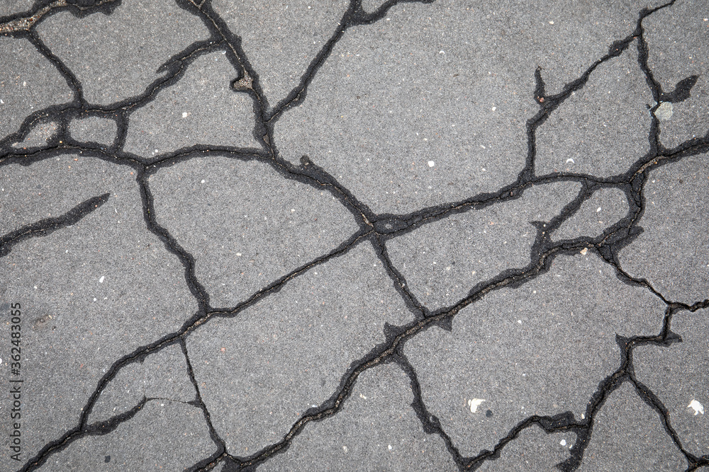 Obraz premium Cracked asphalt pavement. Traffic, road repairs, weather and poor quality concept