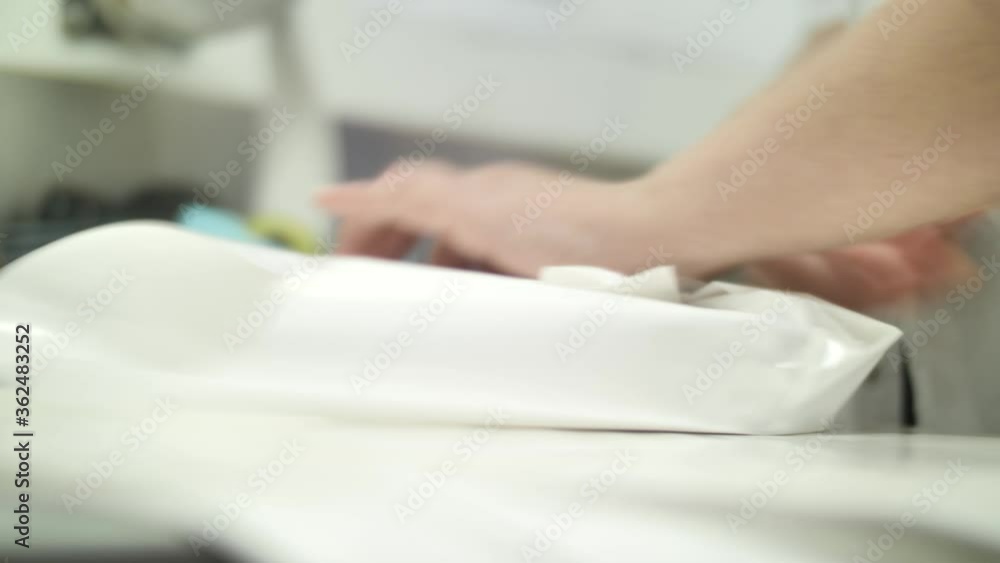 Hands of manufacture worker packing block of maturing blue cheese in paper Hands of manufacture worker packing block of maturing blue cheese in paper