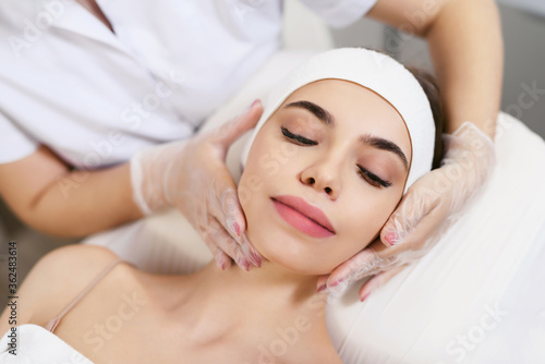 Beautician performs facial massage for a young woman in a beauty clinic or spa salon. Cosmetology treatment. Perfect skin concept. Eternal youth.