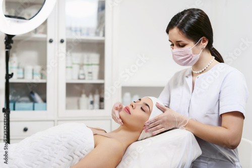 Beautician performs facial massage for a young woman in a beauty clinic or spa salon. Cosmetology treatment. Perfect skin concept. Eternal youth.