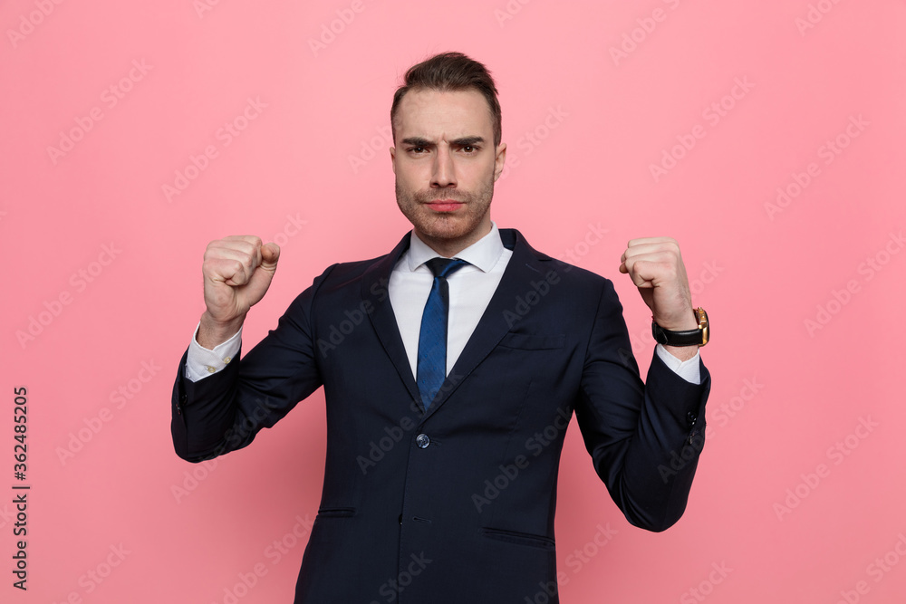 young elegant businessman in suit holding fists up young elegant businessman in suit holding fists up