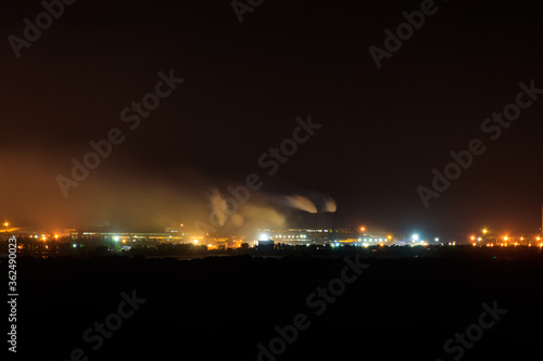 Night view of industrial district of the city and smoke pipes of factory