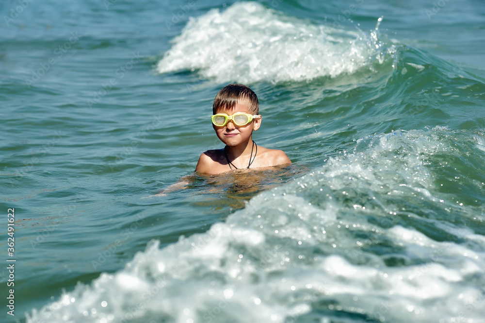 A happy boy is swimming in the sea . Children's holiday at the sea