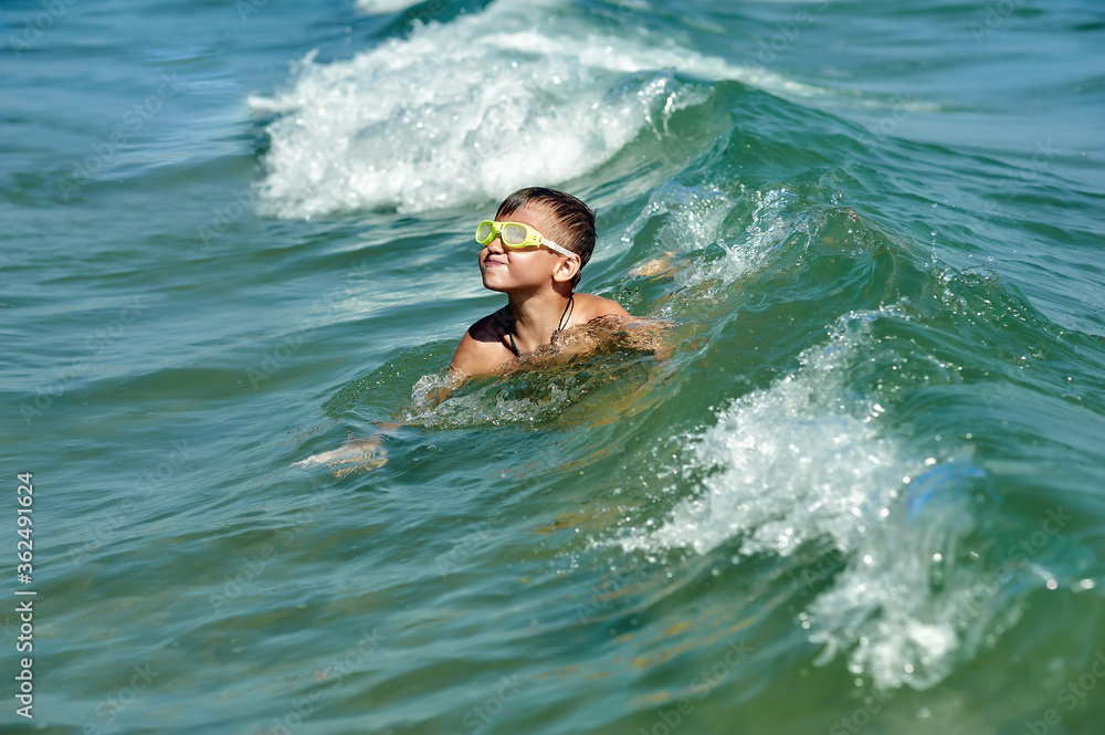 A happy boy is swimming in the sea . Children's holiday at the sea