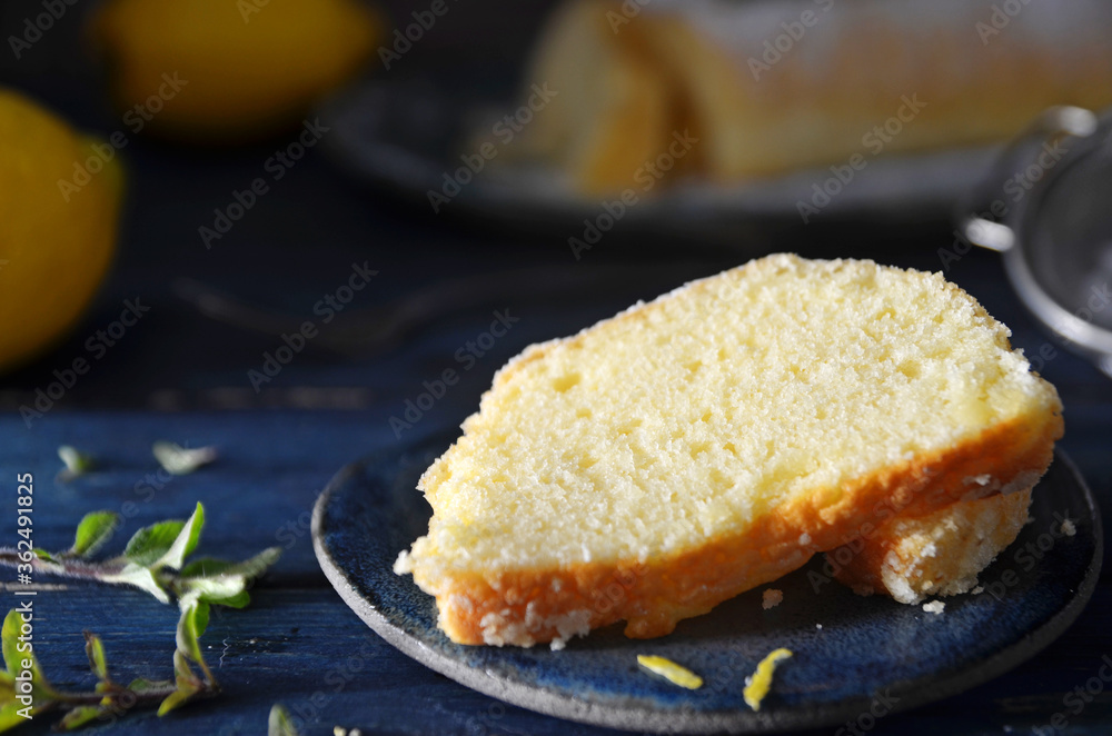 A piece of lemon cake on a saucer against a blue background