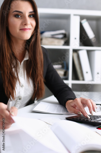 Businesswoman in the office keeps her hand on the calculator makes financial analysis and counting of expenses and incomes of the enterprise forms a report on the work done for the reporting period photo