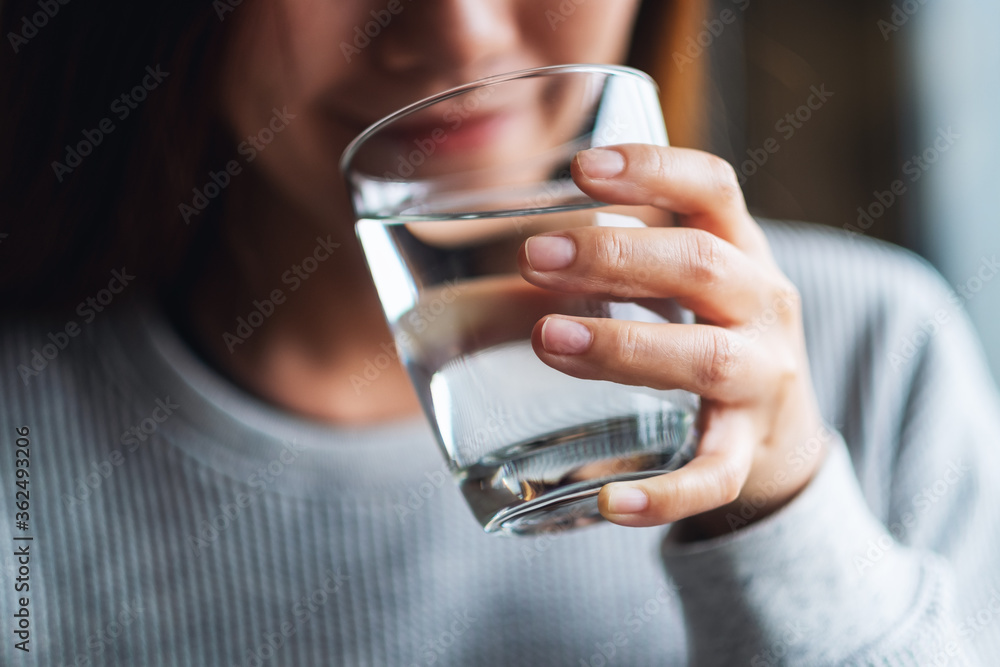 Closeup image of a beautiful young asian woman holding a glass of water to drink - obrazy, fototapety, plakaty 