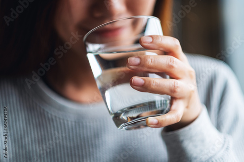 Murais de parede Closeup image of a beautiful young asian woman holding a glass of water to drink