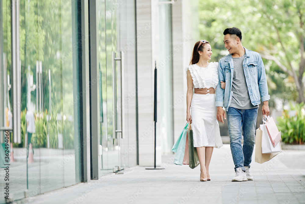 Smiling young boyfriend and girlfriend with shopping bags walking in the street with shopping bags Smiling young boyfriend and girlfriend with shopping bags walking in the street with shopping bags