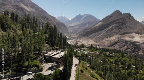 Stunning green Hunza valley surrounded by arid mountains with the snowy Rakaposhi peak in the background, forward moving aerial view near Karimabad, Gilgit Baltistan, Pakistan